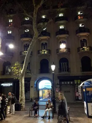 people sitting in benches in front of a building at night at Hotel Toledano Ramblas in Barcelona