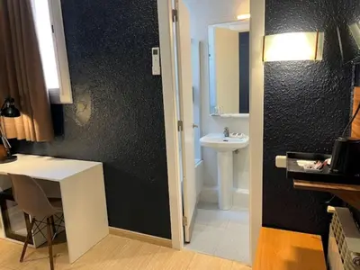 a bathroom with a toilet and a black door at Hostal Iznájar Barcelona in Barcelona