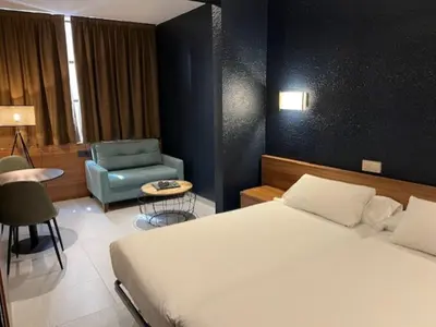 a bedroom with a bed and a blue chair at Hostal Iznájar Barcelona in Barcelona