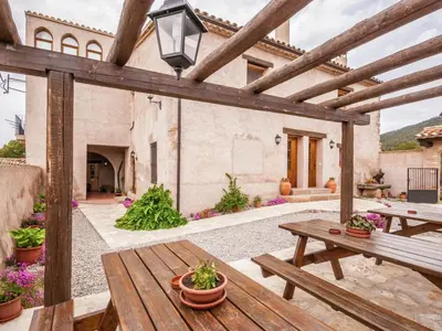 an outdoor patio with a wooden table and benches at Cottage in Maians with Sea View & Pool in Castellfullit del Boix