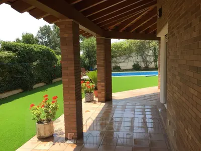 an outdoor patio with a brick wall and green lawn at BarcelonaVacances-Villa Lucia in San Pol de Mar