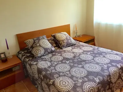 a bed with a blue and white comforter and pillows at BarcelonaVacances-Villa Lucia in San Pol de Mar