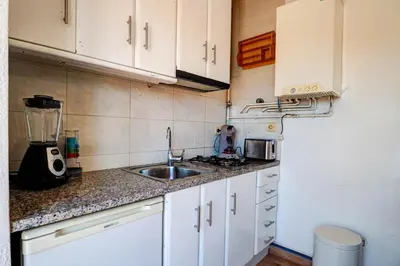 a kitchen with white cabinets and a sink at Secret Garden Apartment by Hello Homes Sitges in Sitges