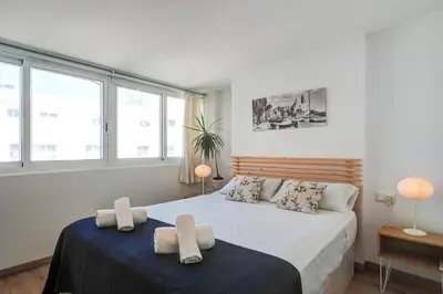 a bedroom with a large bed and two windows at Secret Garden Apartment by Hello Homes Sitges in Sitges