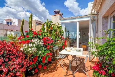a patio with a table and flowers on a balcony at Secret Garden Apartment by Hello Homes Sitges in Sitges
