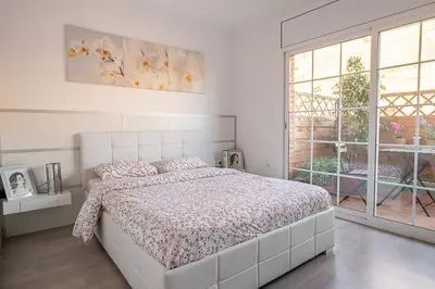 a white bedroom with a bed and a window at Kamelly in Badalona