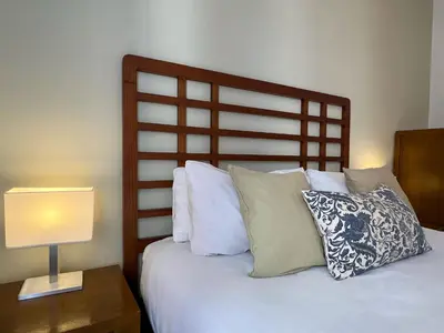 a bed with a wooden headboard next to a table with a lamp at Stay U-nique Apartments Begur in Barcelona