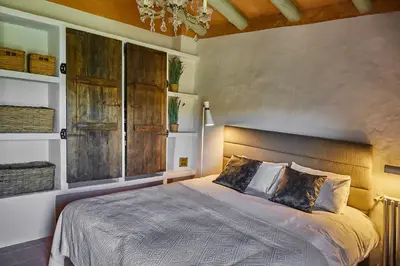 a bedroom with a large bed and a chandelier at Manor House at Masia Nur Sitges, Adults only in Canyelles
