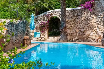 a swimming pool in front of a stone wall at Manor House at Masia Nur Sitges, Adults only in Canyelles