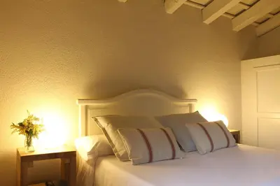 a bedroom with a bed with white pillows and two lamps at Can Barrina in Montseny