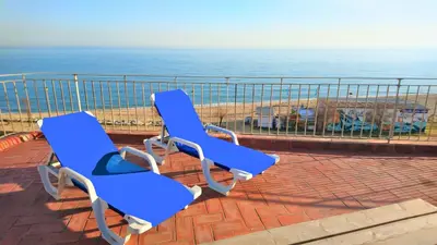two blue chairs sitting on a brick patio overlooking the ocean at MARILU SEAVIEW & BEACH - apartment in Masnou