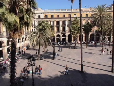 a large building with palm trees and people in a courtyard at Pensión Villanueva in Barcelona