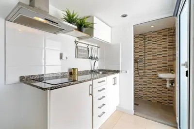 a kitchen with white cabinets and a sink and a couch at Rooftop Terrace BBQ in Gràcia AC in Barcelona