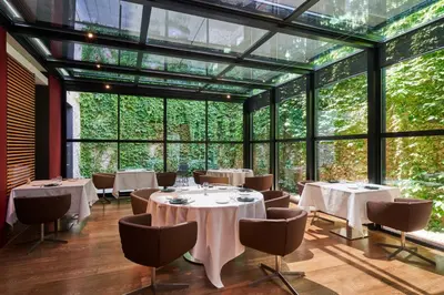 a restaurant with tables and chairs and large windows at Mercer Casa Torner i Güell in Vilafranca del Penedès