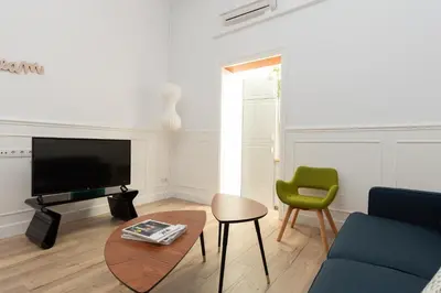 a living room with a couch and a table and a tv at Casa Cosi - Eixample 1 in Barcelona