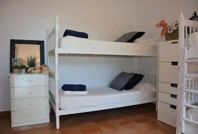 a bedroom with two bunk beds and a dresser at Villa Sitges Colibri at 10 min Walk Beaches - Center City Amaizing Garden Pool XXL Private Tenis Piste in Vilanova i la Geltrú