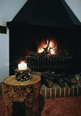 a fireplace with a candle and a table in front of it at El Porxo de Can Baixeres PB-00318 in Montseny