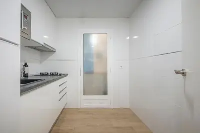 a white kitchen with a sink and a door at Apartamento a 100 metros de la playa in Pineda de Mar