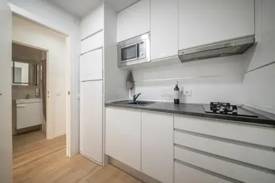 a white kitchen with a sink and a microwave at Apartamento a 100 metros de la playa in Pineda de Mar