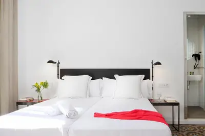 a large white bed with a red dress on it at Som Nit Triomf in Barcelona