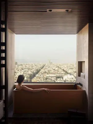 a woman sitting in a bath tub looking out a window at Nobu Hotel Barcelona in Barcelona