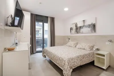 a white bedroom with a bed and a tv at Hostal House in Barcelona