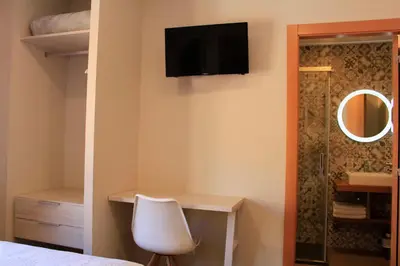 a white desk and a chair next to a cabinet at Hostal La Romànica in Sabadell