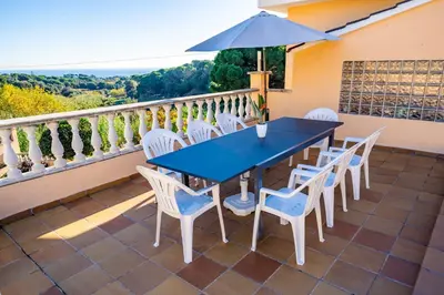 a blue table and chairs on a balcony with an umbrella at HomeHolidaysRentals Aube in Sant Cebrià de Vallalta