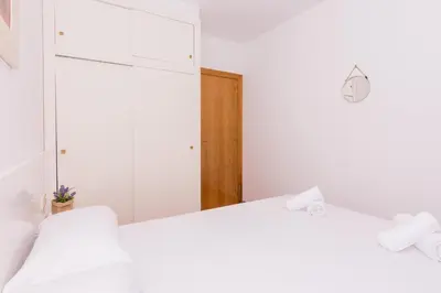 a white bedroom with two beds and a closet at HomeHolidaysRentals Aube in Sant Cebrià de Vallalta