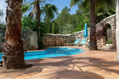 a swimming pool in a yard with palm trees at Casa Los Arcos at Masia Nur Sitges, Adults only in Canyelles