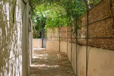 an alley way with a brick wall and trees at Casa Los Arcos at Masia Nur Sitges, Adults only in Canyelles