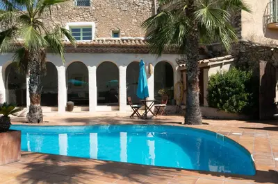 a swimming pool in front of a house with palm trees at Casa Marqués at Masia Nur Sitges, Adults only in Canyelles