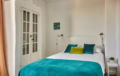 a bedroom with a bed with blue and yellow pillows at Casa Granada at Masia Nur Sitges, with private pool and adults only in Canyelles