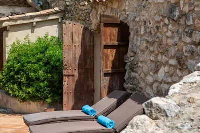 a wooden door with a bench in front of a stone wall at Casa Jasmin at Masia Nur Sitges, Adults only in Canyelles