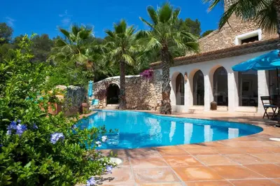 a swimming pool in front of a house with palm trees at Villa Hermosa at Masia Nur Sitges, Adults only in Canyelles