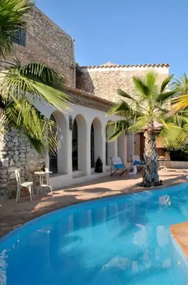 a swimming pool in front of a house with palm trees at Casa Azul at Masia Nur Sitges, Adults only in Canyelles