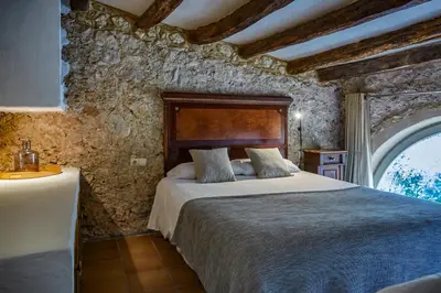 a bedroom with a bed in a stone wall at Casa Olivo at Masia Nur Sitges, Adults only in Canyelles