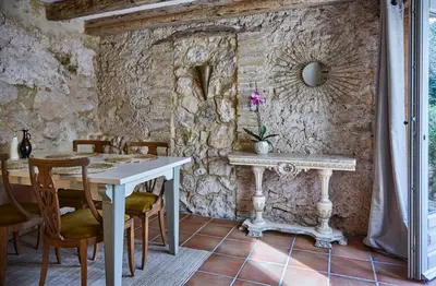 a dining room with a table and a stone wall at Casa Olivo at Masia Nur Sitges, Adults only in Canyelles
