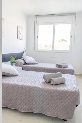 three beds in a white room with a window at Apartamento Montroig 2 in Sitges
