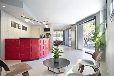 a lobby with a red wall and a table and chairs at Hotel Brick Barcelona in Barcelona