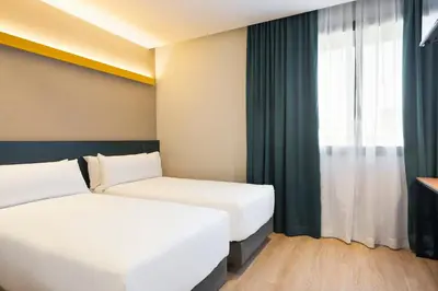 two beds in a hotel room with a window at Hotel Brick Barcelona in Barcelona
