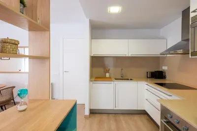 a kitchen with white cabinets and a wooden table at Sitges Centre. Simply Charming in Sitges
