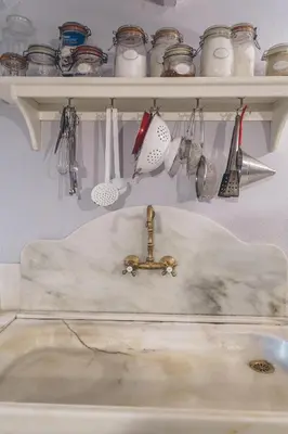 a kitchen sink with utensils on a shelf above it at Casa Baulenas in Caldes d'Estrac