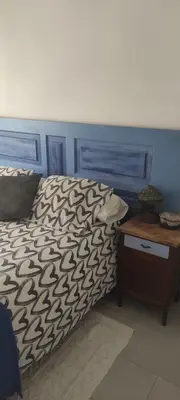 a bed with a blue headboard and a wooden table at BLAU in Masnou