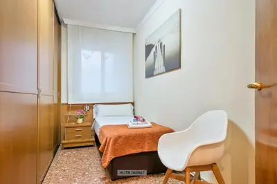 a small bedroom with a bed and a white chair at Alcam Barbera Centro in Barbera del Valles
