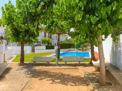 two benches under trees next to a swimming pool at Holiday Home Katy by Interhome in Cunit