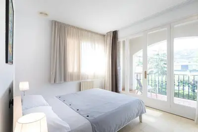 a white bedroom with a bed and a large window at Villa Paquita in Calella