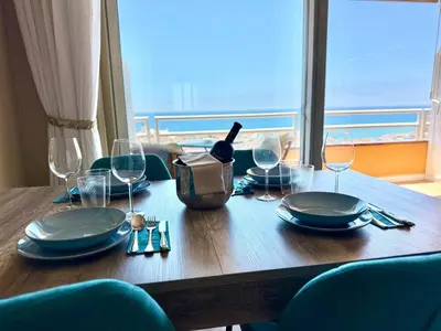 a wooden table with plates and wine glasses on it at APARTAMENTO MARINERO, Vistas impresionantes. in Sitges
