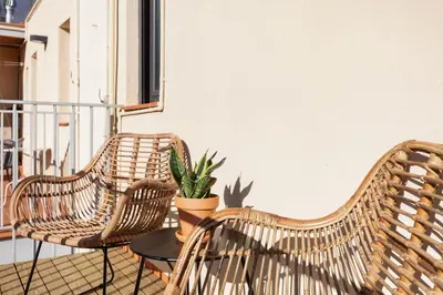 three wicker chairs and a table on a balcony at Ola Living Calabria in Barcelona