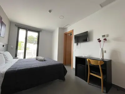a bedroom with a bed and a desk and a television at 6 Bis HOTEL in Castelldefels